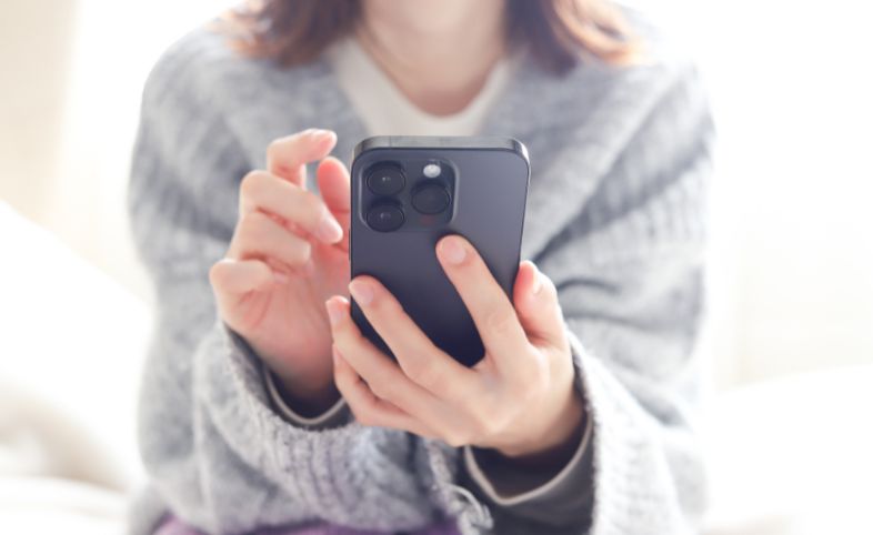 Person in grey jumper holding their phone